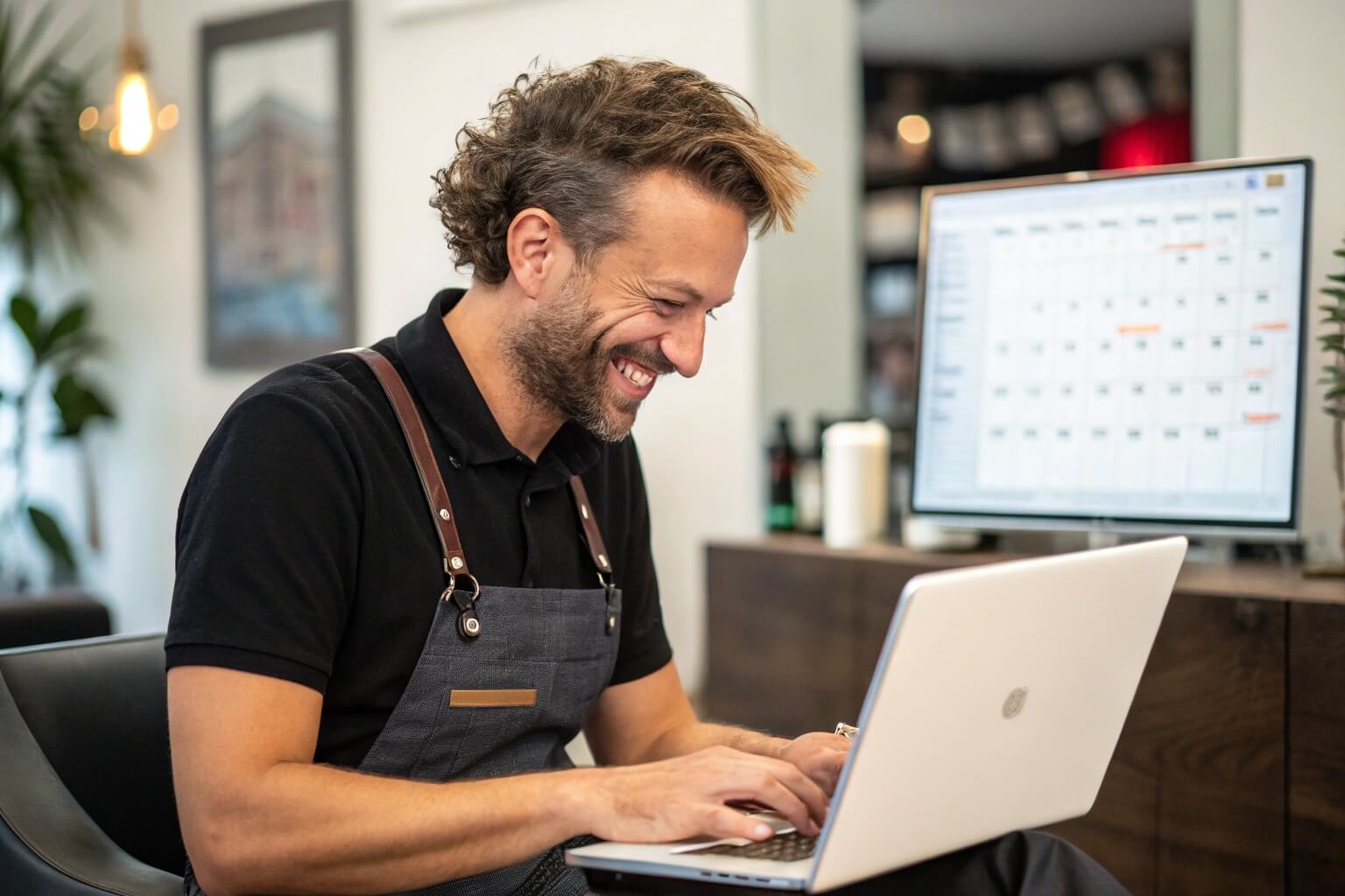 Friseur mit Laptop freut sich über den Onlinekalender